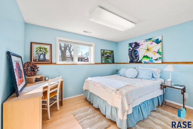 bedroom with visible vents, baseboards, and wood finished floors