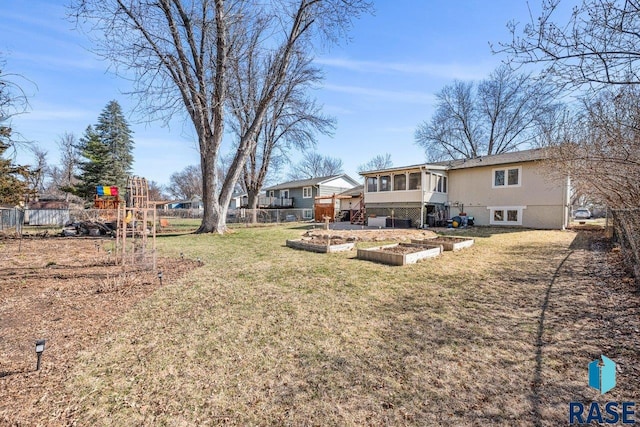 view of yard with a sunroom, fence, and a vegetable garden