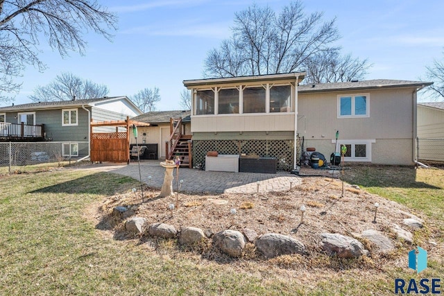 rear view of property with fence, a patio, a sunroom, and a lawn