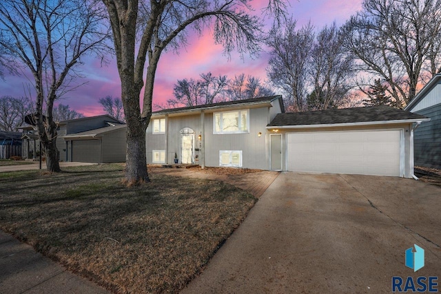 view of front of house with an attached garage, a yard, and concrete driveway