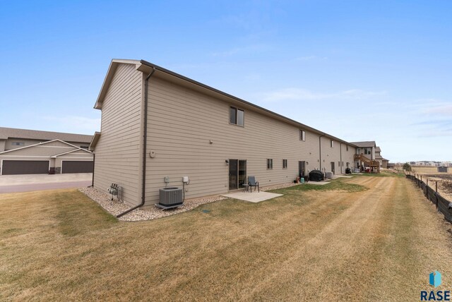 rear view of property featuring a patio area, fence, central AC unit, and a lawn