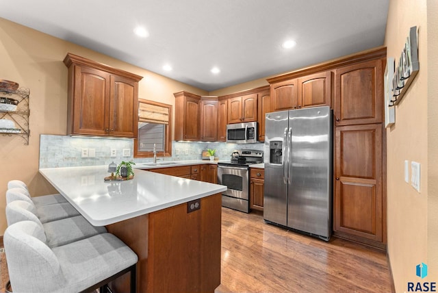 kitchen with tasteful backsplash, appliances with stainless steel finishes, light wood-style floors, and a kitchen breakfast bar