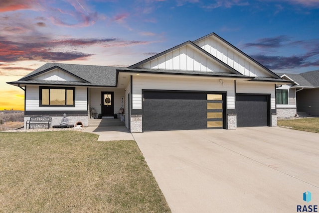 view of front facade with a yard, stone siding, a garage, board and batten siding, and concrete driveway