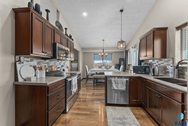 kitchen featuring an inviting chandelier, light wood-style flooring, a sink, hanging light fixtures, and stainless steel appliances
