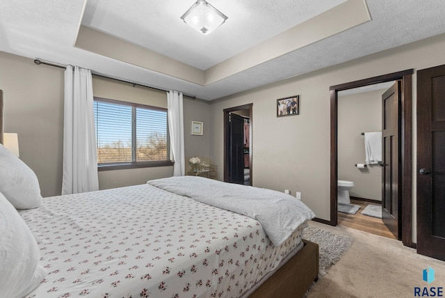 carpeted bedroom featuring a spacious closet, a raised ceiling, connected bathroom, and baseboards