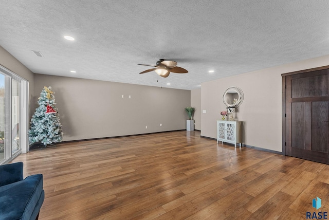 living room featuring visible vents, baseboards, a ceiling fan, and wood finished floors