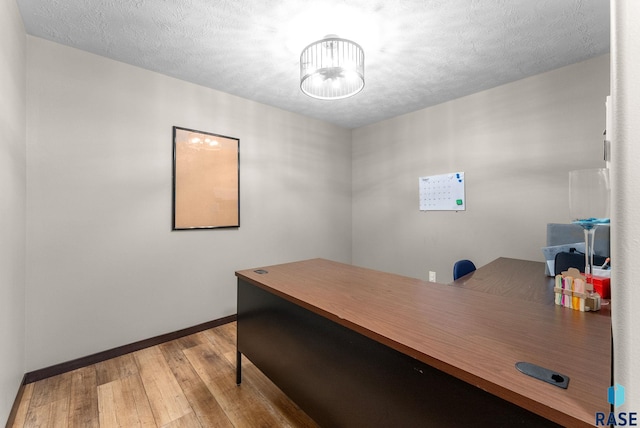 office with wood-type flooring, baseboards, and a textured ceiling