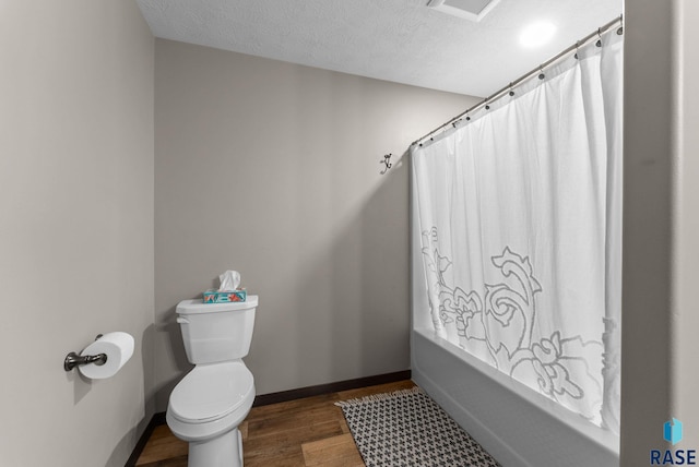 full bathroom with a textured ceiling, toilet, shower / bath combo, wood finished floors, and baseboards