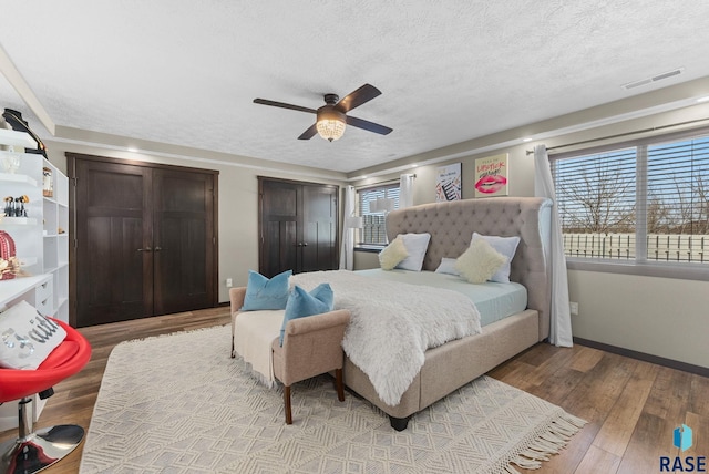 bedroom featuring light wood-style flooring, multiple windows, a textured ceiling, and visible vents