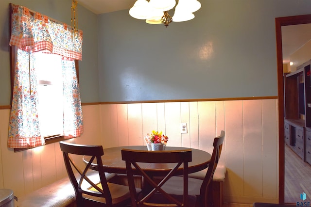 dining area with a wainscoted wall and an inviting chandelier