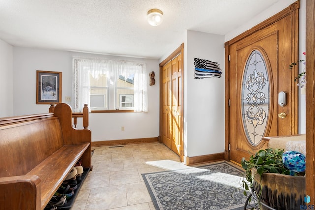entrance foyer with a textured ceiling, light tile patterned floors, and baseboards