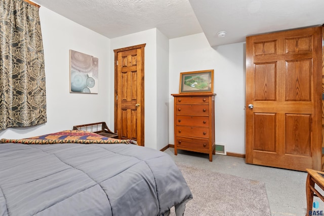 bedroom featuring light colored carpet, baseboards, a textured ceiling, and visible vents