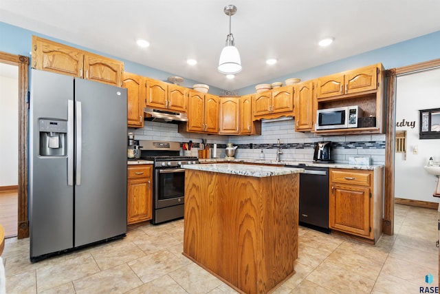 kitchen featuring a kitchen island, under cabinet range hood, stainless steel appliances, decorative light fixtures, and backsplash