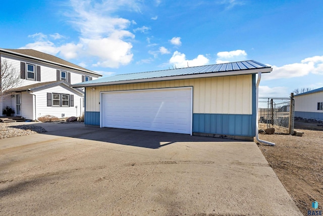 view of front of property featuring fence, an outdoor structure, metal roof, and a garage