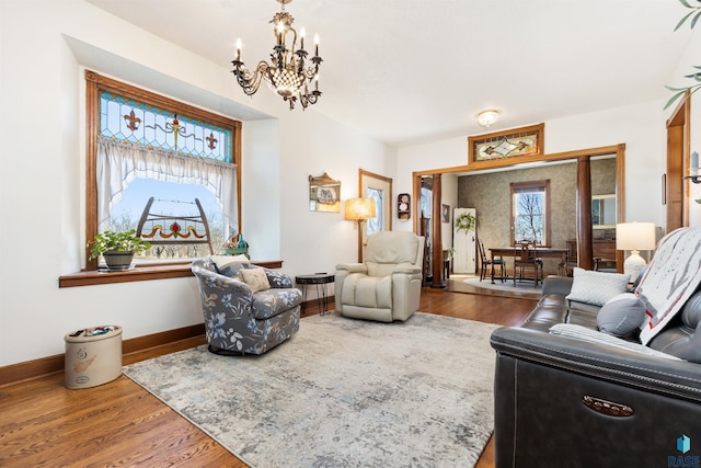 living room featuring wood finished floors, a notable chandelier, and baseboards