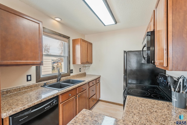 kitchen featuring brown cabinetry, light countertops, a sink, and black appliances