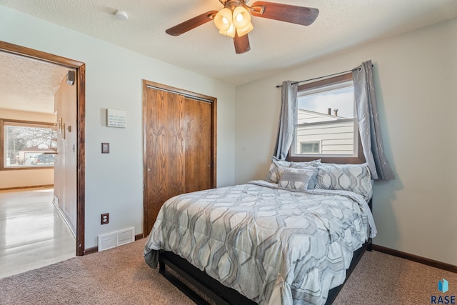 carpeted bedroom featuring ceiling fan, a textured ceiling, a closet, visible vents, and baseboards