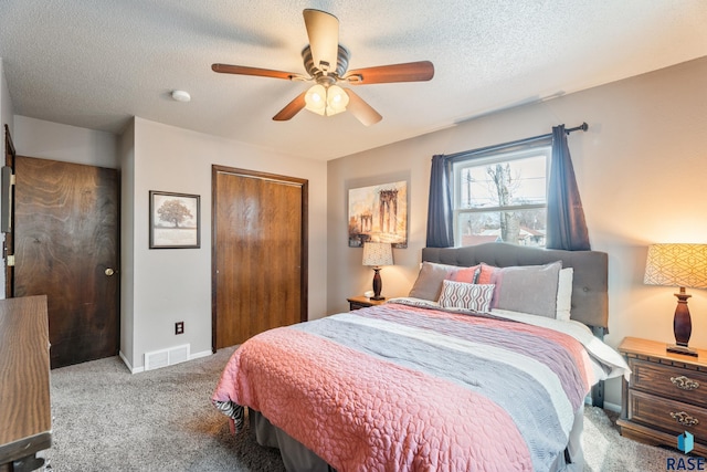 bedroom featuring a closet, a textured ceiling, visible vents, ceiling fan, and carpet
