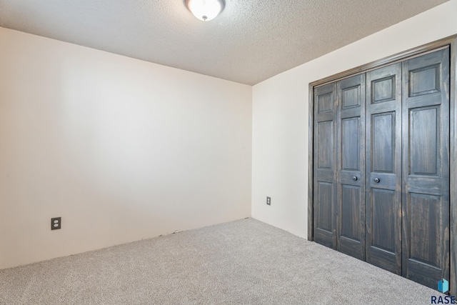 unfurnished bedroom with a closet, carpet flooring, and a textured ceiling