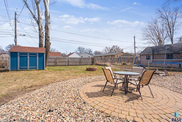 view of patio / terrace featuring a storage shed, an outbuilding, a fenced backyard, and a fire pit