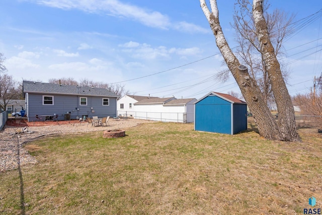 view of yard with an outbuilding, fence, a fire pit, and a shed