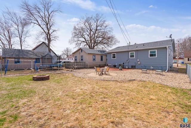 back of house featuring crawl space, a yard, fence private yard, an outdoor fire pit, and a trampoline