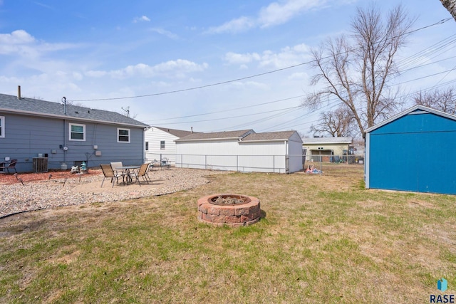 view of yard featuring a shed, an outdoor structure, an outdoor fire pit, fence, and central AC unit