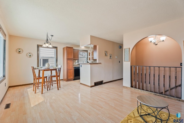 kitchen featuring brown cabinetry, light wood-style floors, dishwasher, and visible vents