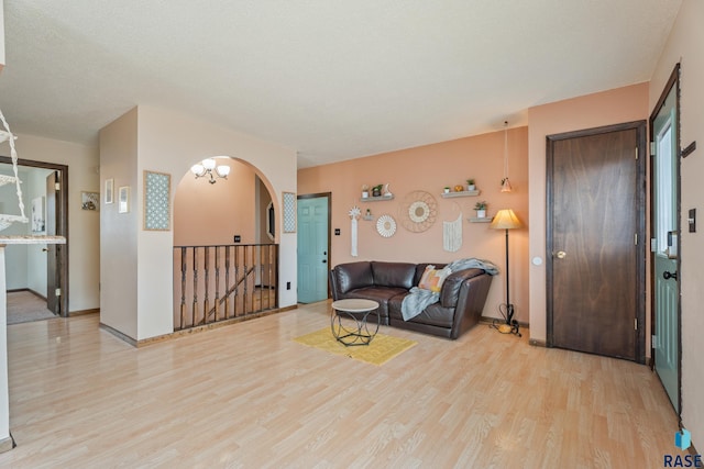 living room with arched walkways, light wood-type flooring, and baseboards