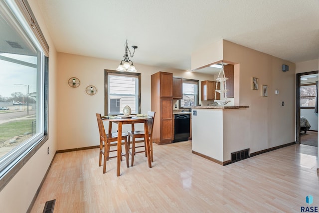 kitchen with visible vents, brown cabinetry, light wood finished floors, and dishwasher