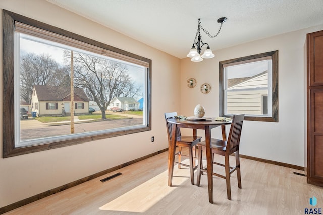 dining space with a chandelier, light wood finished floors, baseboards, and visible vents