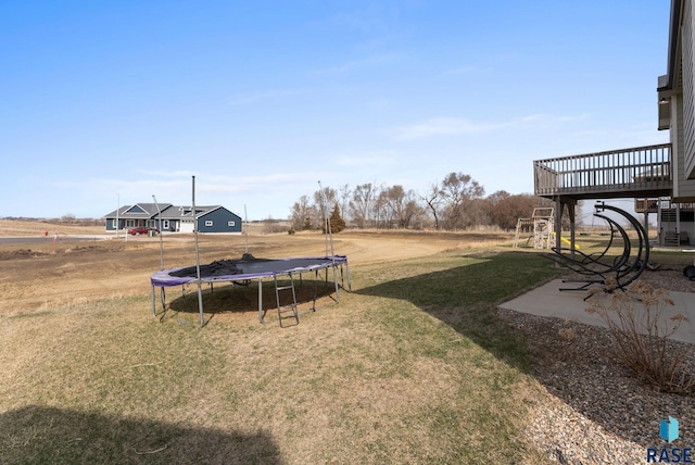 view of yard with a trampoline and a wooden deck