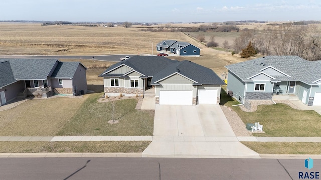 129 Lynx St, Valley Springs, SD 57068 - view of front facade with a rural view, a front yard, stone siding, an attached garage, and driveway