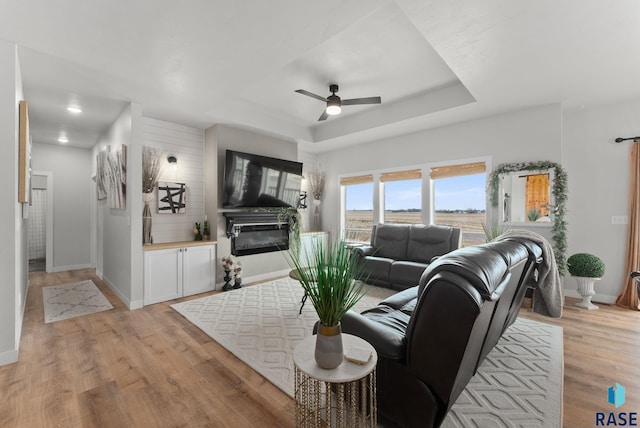 living room with baseboards, a ceiling fan, and a glass covered fireplace