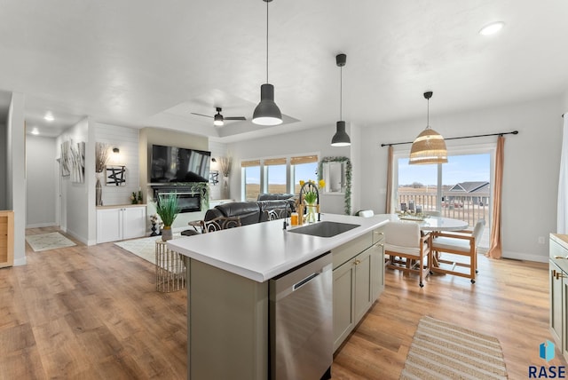 kitchen featuring dishwasher, a sink, open floor plan, light countertops, and a ceiling fan