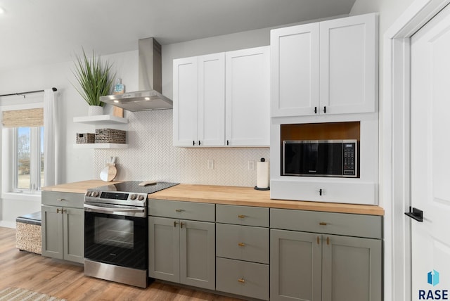 kitchen with stainless steel appliances, gray cabinetry, wood counters, and wall chimney exhaust hood