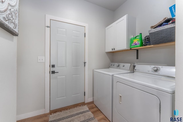 clothes washing area featuring cabinet space, baseboards, light wood finished floors, and washer and dryer