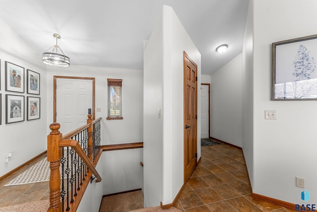 hall with baseboards and an upstairs landing
