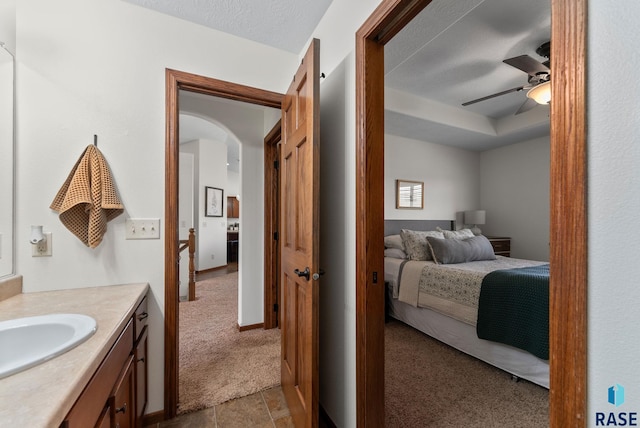 interior space with vanity, baseboards, a textured ceiling, connected bathroom, and ceiling fan