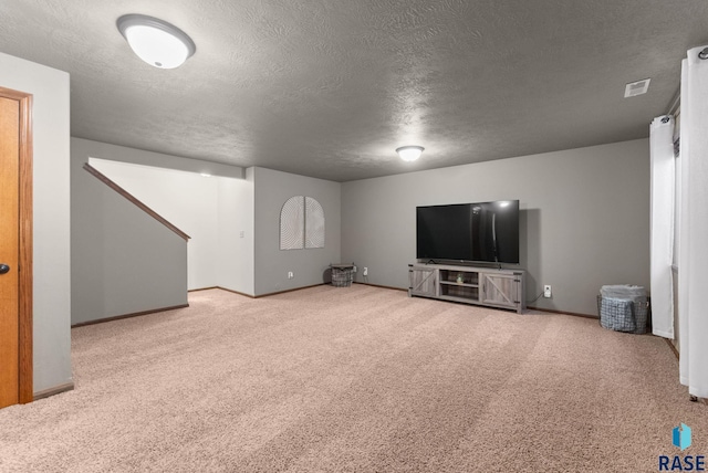 unfurnished living room with carpet, baseboards, and a textured ceiling