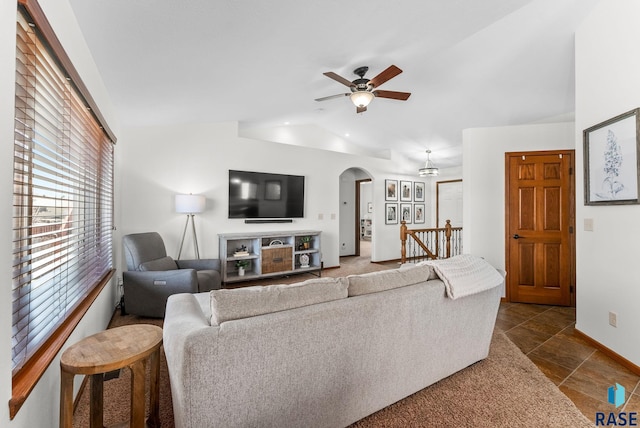 living room featuring baseboards, a ceiling fan, arched walkways, and vaulted ceiling