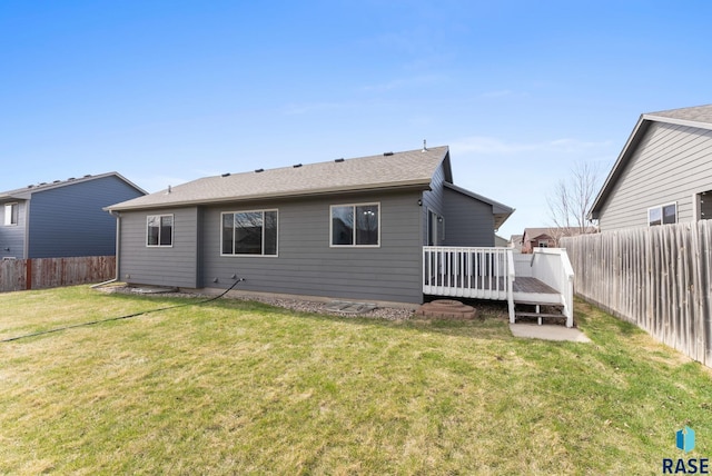 rear view of house featuring a yard, roof with shingles, a fenced backyard, and a wooden deck