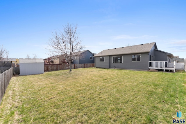 view of yard featuring a shed, a deck, a fenced backyard, and an outdoor structure