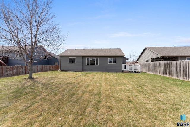 rear view of house with a fenced backyard and a lawn