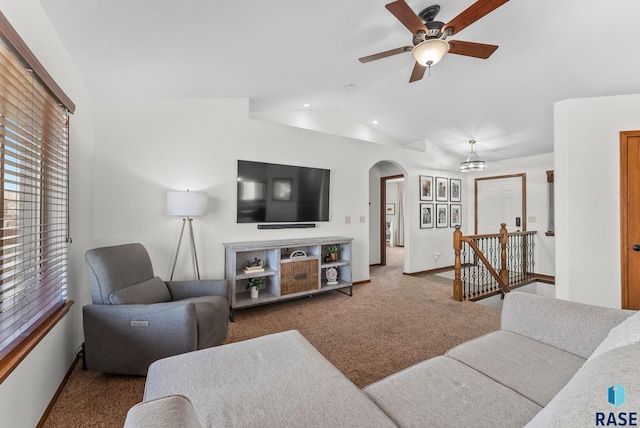 carpeted living room featuring baseboards, arched walkways, vaulted ceiling, and a ceiling fan