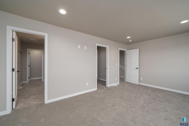 unfurnished bedroom with recessed lighting, carpet, baseboards, and a walk in closet