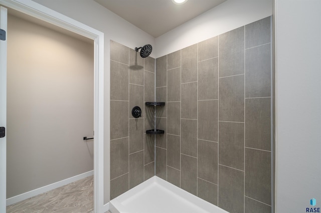 full bath with a tile shower and baseboards