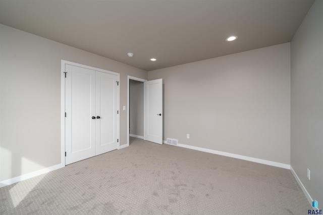 unfurnished bedroom featuring a closet, baseboards, recessed lighting, visible vents, and light colored carpet