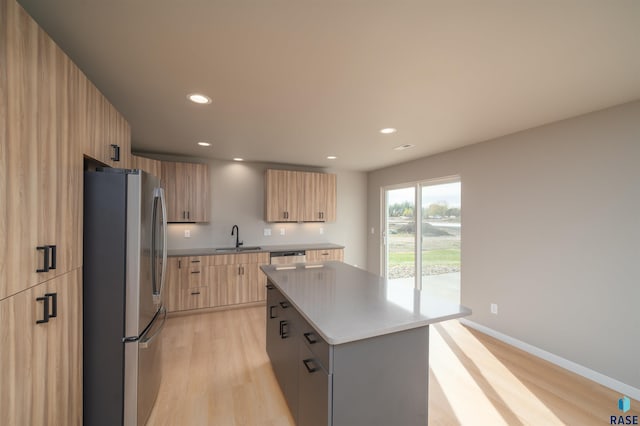 kitchen with light brown cabinets, a center island, modern cabinets, stainless steel appliances, and a sink