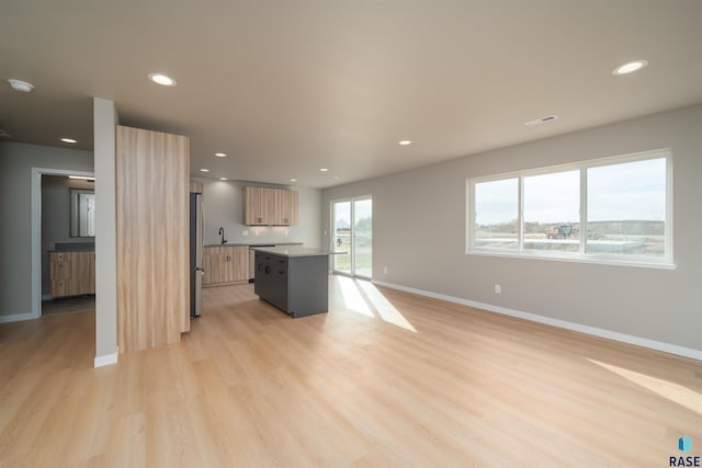 interior space featuring light wood-type flooring, visible vents, recessed lighting, a sink, and baseboards